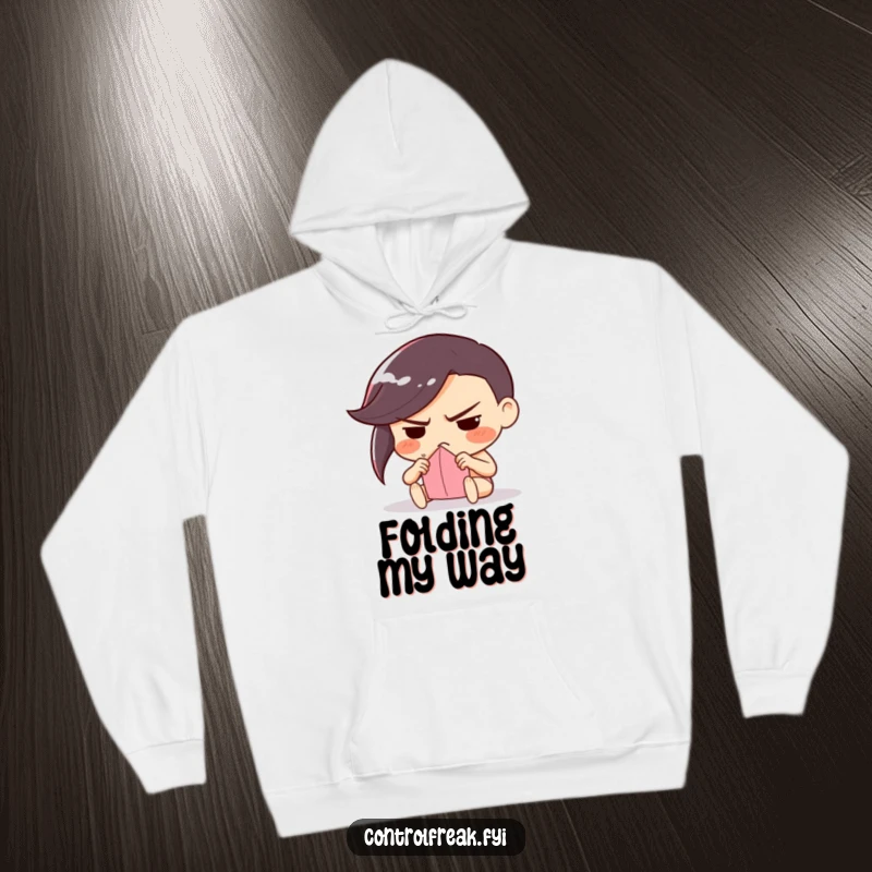 Funny hoodie showing a character with a determined frown, meticulously folding a piece of paper, perfect for focused crafters.